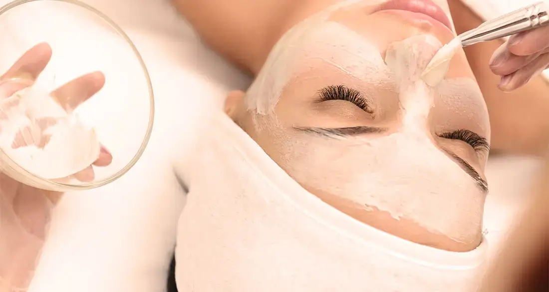 Femeie relaxându-se în timpul unui tratament facial profesional, pentru o piele mai fermă și hidratată.